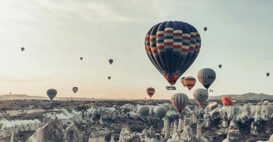 Nightlife Experience Cappadocia - Multicolored hot air balloons flying above famous vast rocky valley in Cappadocia Turkey on early morning on fair weather