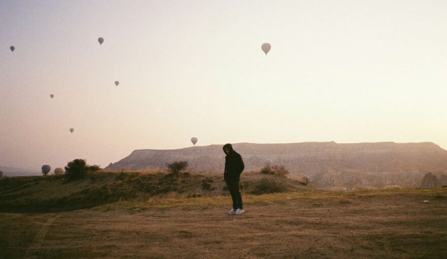 Nightlife Entertainment Cappadocia - a man standing in a field with hot air balloons in the sky