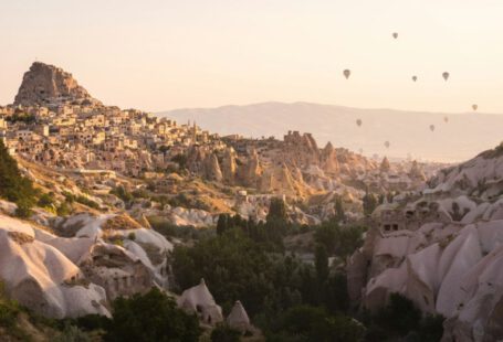 Village Experience Cappadocia - a group of hot air balloons flying over a rocky landscape