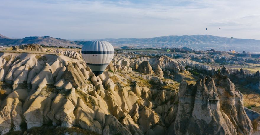 Stay Connected Cappadocia - White and Blue Striped Hot Air Balloon on Rocky Mountain