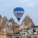 Turkish Spirits Cappadocia - a blue and white hot air balloon flying over a city
