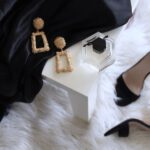 Luxury Boutique Ürgüp - pair of gold-colored earrings on table and black ankle-strap pumps on area rug