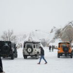 Cappadocia Winter Adventure - a group of people walking in the snow next to a group of vehicles