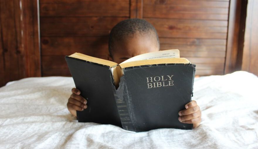 Pilgrimage Early Christian Churches - boy reading Holy Bible while lying on bed