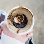 Turkish Coffee Divination - a person holding a cup with a chocolate swirl in it