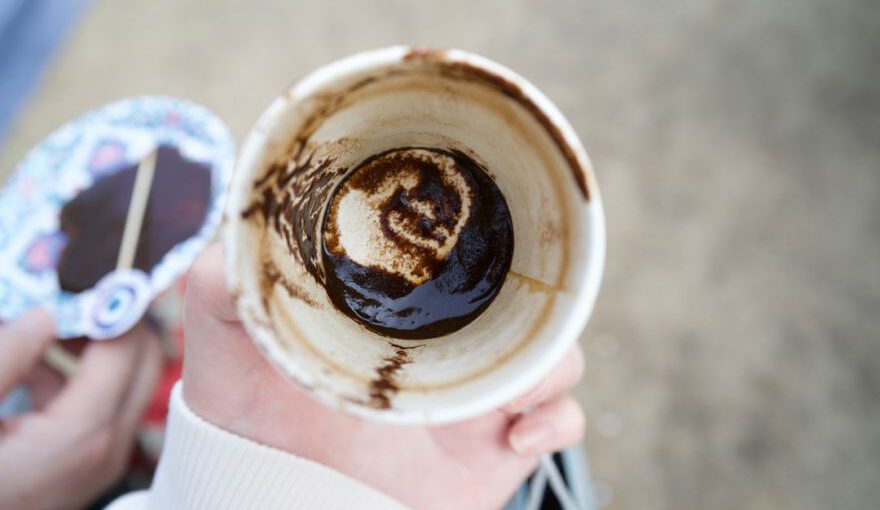 Turkish Coffee Divination - a person holding a cup with a chocolate swirl in it