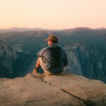 Outdoor Activities - man in black t-shirt and brown hat sitting on rock