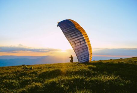 Paragliding - silhouette of person riding parachute during sunset