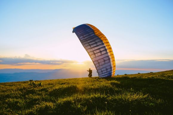 Paragliding - silhouette of person riding parachute during sunset