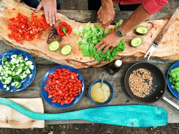 Cooking Classes - person slicing green vegetable in front of round ceramic plates with assorted sliced vegetables during daytime