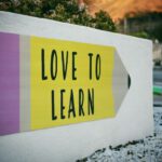 Learning Language - love to learn pencil signage on wall near walking man