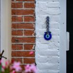 Evil Eye - purple flower on brown brick wall