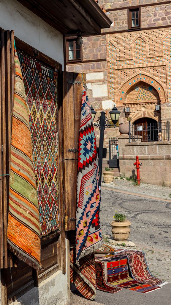 Colorful Turkish carpets hanging outside a traditional shop on a sunny day.