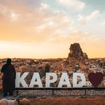 Woman enjoying a spectacular sunset view over Uchisar Castle in Cappadocia, Turkey.
