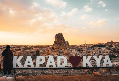 Woman enjoying a spectacular sunset view over Uchisar Castle in Cappadocia, Turkey.