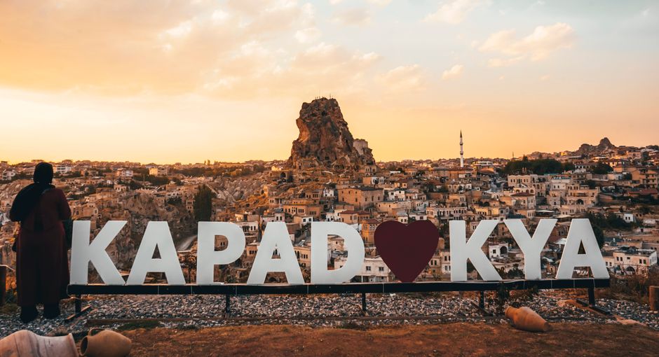 Woman enjoying a spectacular sunset view over Uchisar Castle in Cappadocia, Turkey.
